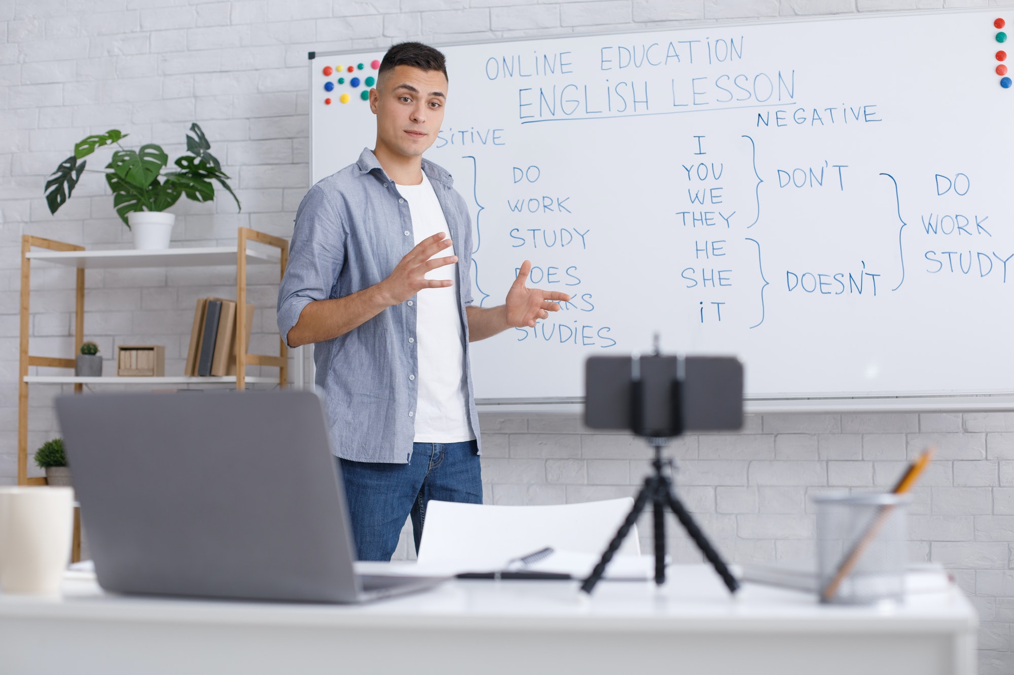 Remote education at home during epidemic. Young man explains rules of English for students, standing